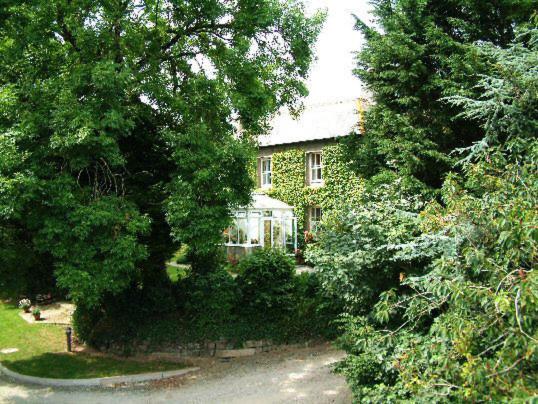een huis wordt omgeven door bomen en struiken bij Bradridge Farm in Launceston