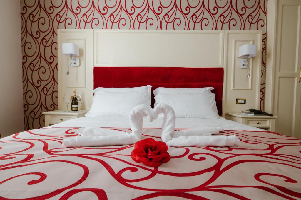 Hotel Città di Parenzo في ترييستي: سرير احمر وبيض عليه وردة حمراء