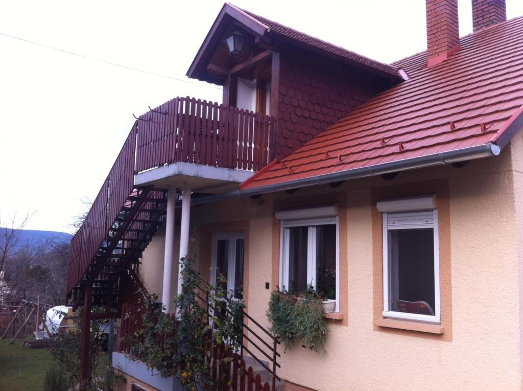 una casa con techo rojo y escalera en Miklai Ház en Szigliget