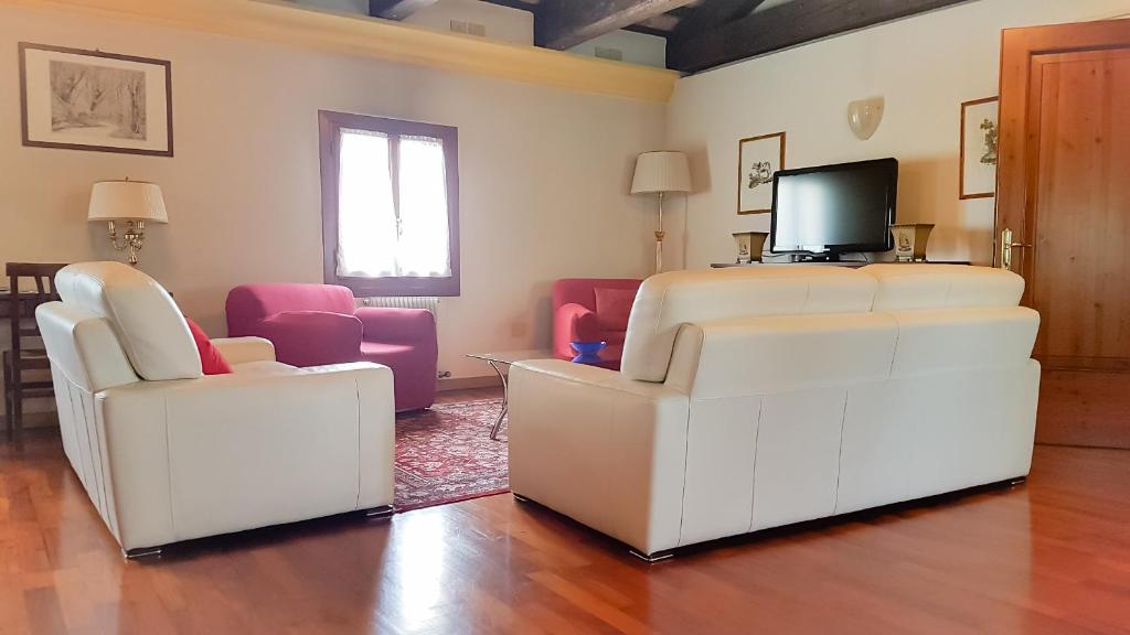 salon z 2 białymi krzesłami i telewizorem w obiekcie Alla Barchessa di Villa Querini w mieście Preganziol