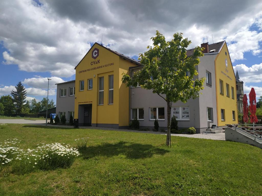 a yellow building with a tree in the yard at Centrum pro vzdělávání a kulturu in Nový Oldřichov