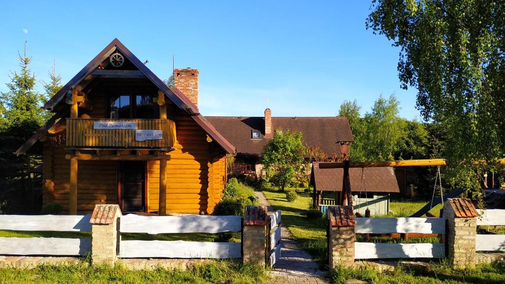una casa de madera con una valla delante de ella en Domki "Pod Sumakiem", en Dębina