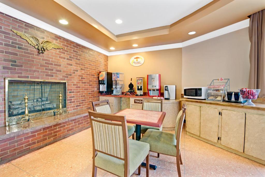 a kitchen with a table and chairs and a brick wall at Super 8 by Wyndham Milford/New Haven in Milford