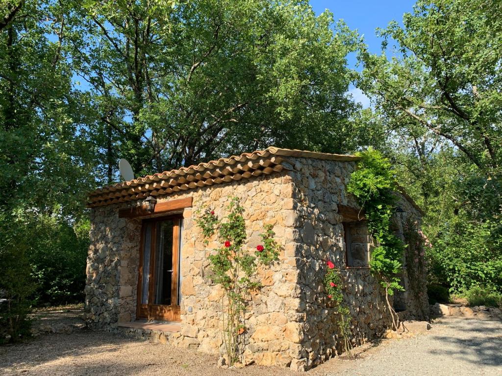 - un petit bâtiment en pierre avec des fleurs dans l'établissement LA BASTIDE DU BAOU, à Callian