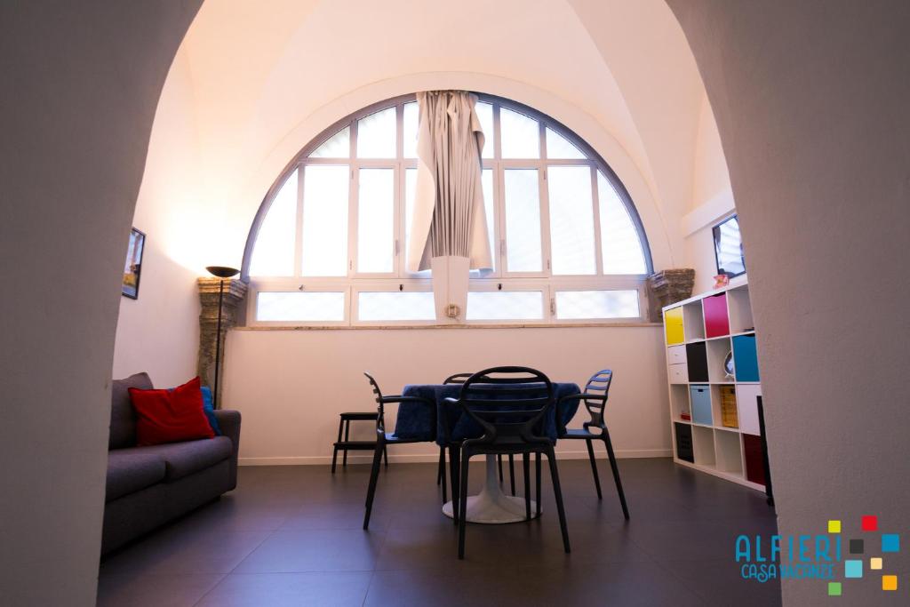 einen Tisch und Stühle in einem Zimmer mit einem großen Fenster in der Unterkunft Casa Vacanze Alfieri in Neapel