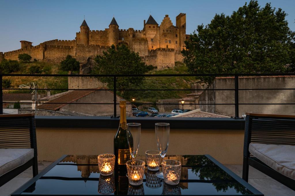 a table with a bottle of wine on a balcony with a castle at Le Loft de La Tour Pinte in Carcassonne