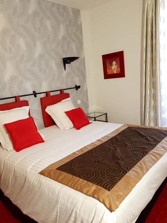 a bedroom with a large bed with red pillows at Hotel Robic - Salles de séminaires & Bar in Pontivy