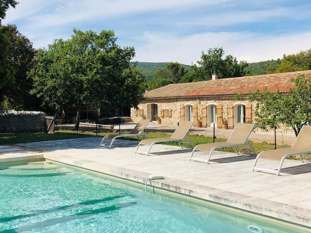 een huis met een zwembad met stoelen en een gebouw bij La Bergerie in Saint-Maximin-la-Sainte-Baume