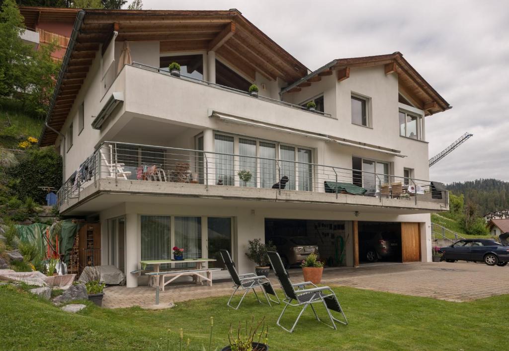 a house with a balcony and chairs in the yard at Grava - Ferienwohnung für max. 2 Personen in Laax