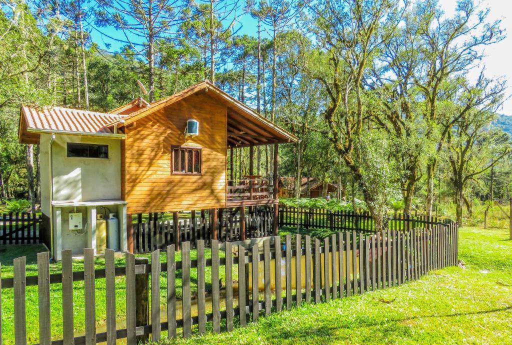 a wooden house with a fence in front of it at Pousada Caminhos da Natureza in Urubici