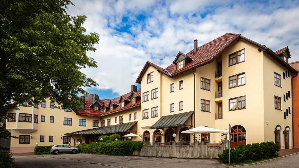 un gran edificio con un coche aparcado delante de él en Hotel Hoyacker Hof, en Garching bei München