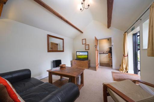 een woonkamer met een bank en een tafel bij The Nook at West Langton lodge in Market Harborough