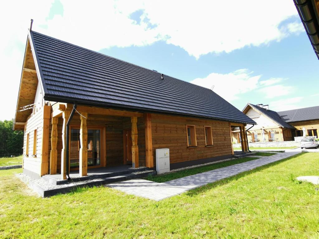 ein Holzhaus mit schwarzem Dach in der Unterkunft Apartamenty Stajnia Ojcowizna in Pokrzywnica