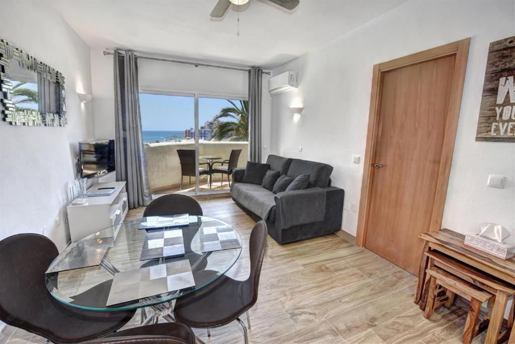 salon ze szklanym stołem i krzesłami w obiekcie Benal Beach, Luxury Sea & Mountain View Beachside 1 Bedroom Apartment w mieście Benalmádena