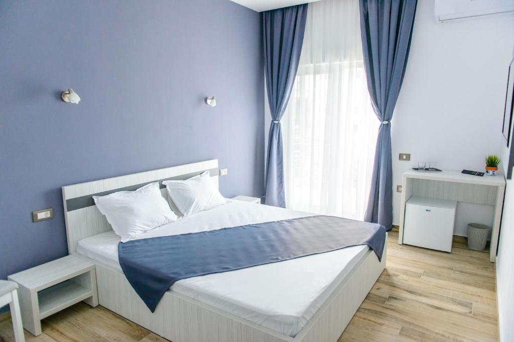 a bedroom with a bed with blue walls and a window at Pensiunea Mara in Techirghiol