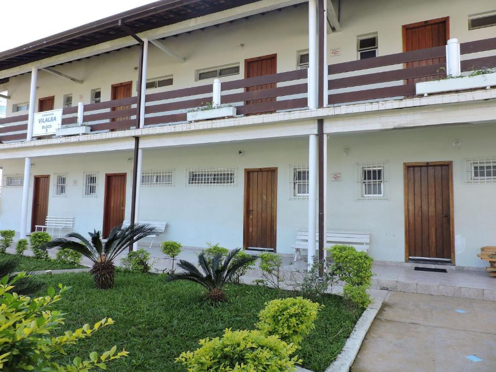 a building with wooden doors and a yard at Condomínio Vilalba in Ubatuba