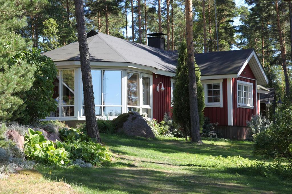 a red cottage in the woods with trees at Villa Vimpasaari in Hamina