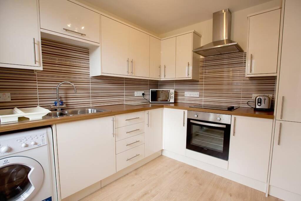 eine Küche mit weißen Schränken, einer Spüle und einem Geschirrspüler in der Unterkunft City Centre Executive 2 Bed Apartment with WiFi & Parking in Aberdeen