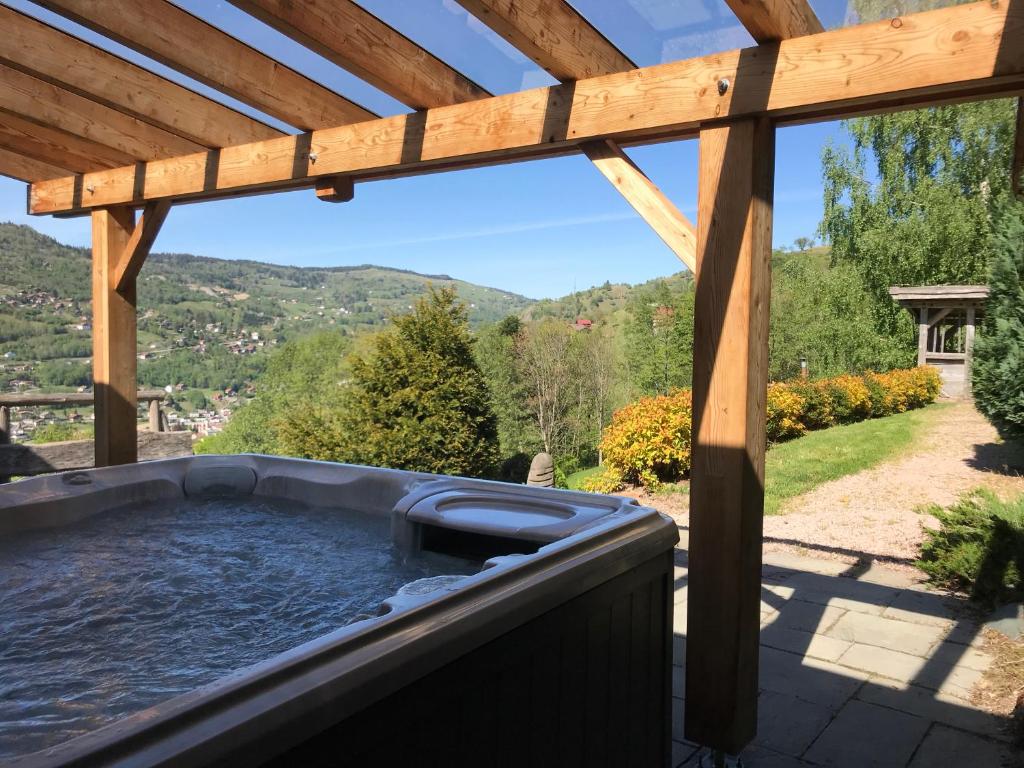 uma banheira de hidromassagem num pátio com uma pérgola de madeira em Les Authentics-Le Retour aux Sources em La Bresse