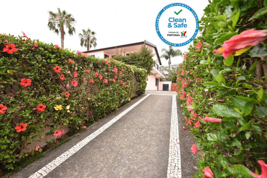 um caminho de jardim com flores e um sinal que diz limpo e seguro em Villa Santana no Funchal
