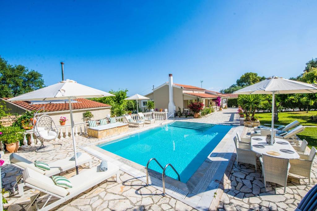 a swimming pool with chairs and umbrellas in a yard at Villa Zapphira Peritheia Corfu in Perítheia