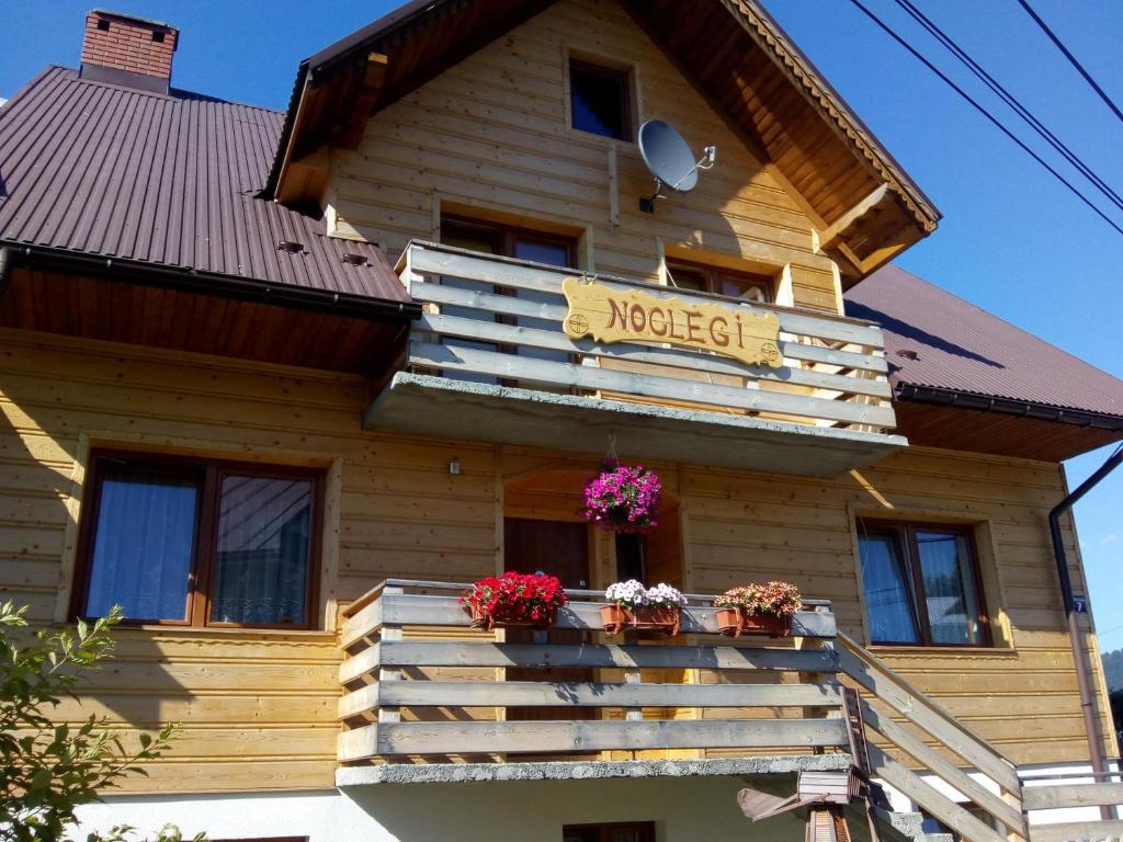 ニエジツァ・ザメクにあるDrewniane pokoje w Niedzicyの木造家屋(花の咲くバルコニー付)