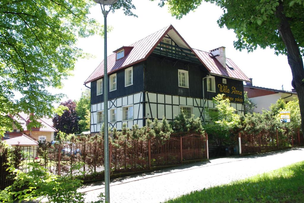 a black and white house with a fence at Willa Anna in Szczawno-Zdrój