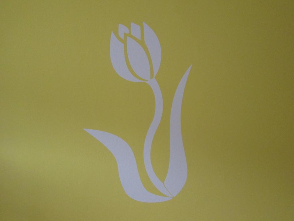 um símbolo branco de uma flor sobre um fundo verde em Lady Tulip - monolocale em Trento
