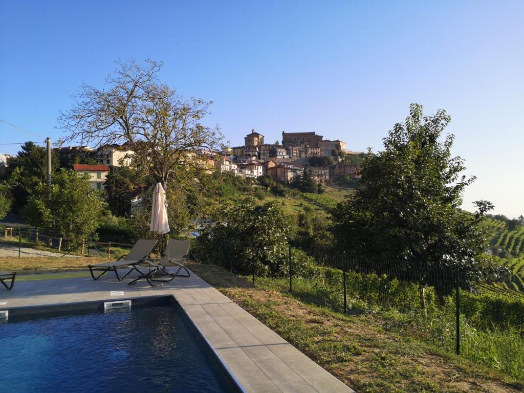 una piscina con 2 sillas y una sombrilla en Locanda Fontanazza Osteria con Camere, en La Morra