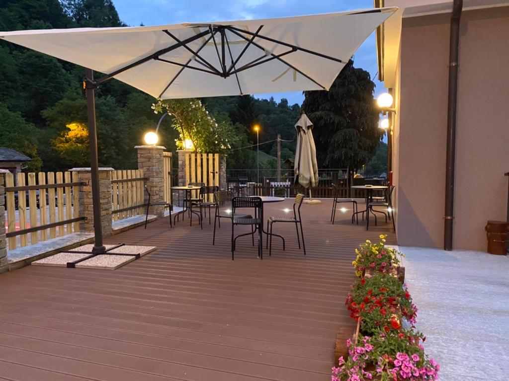 a patio with a table and chairs and an umbrella at Locanda Reloup in Isasca