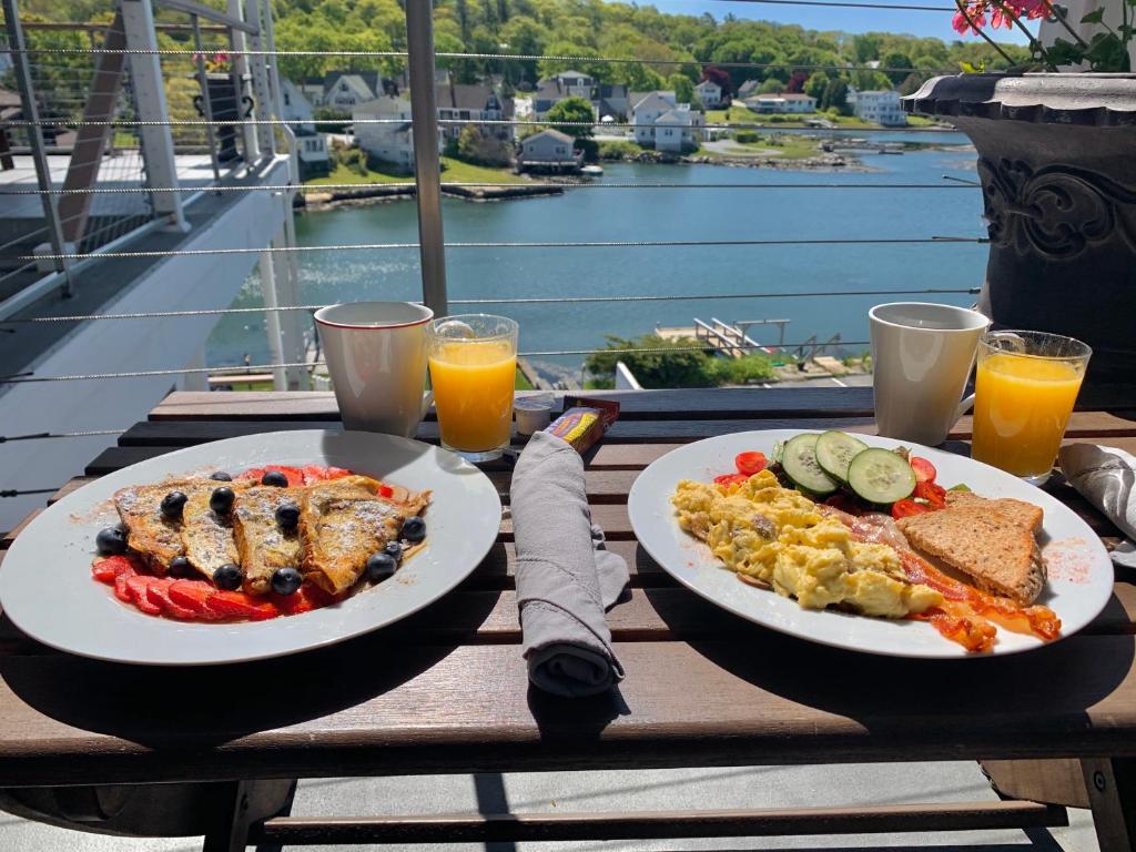 two plates of food on a table with a view of the water at Harborage Inn on the Oceanfront in Boothbay Harbor