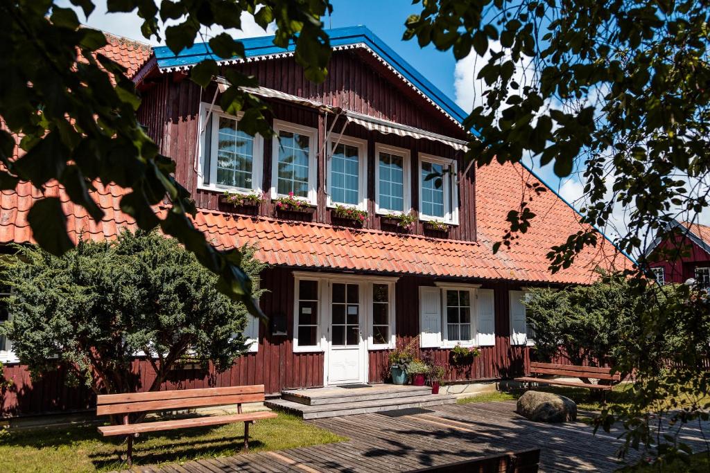 una casa roja con un banco delante en Vila Poilsis Nidoje, en Nida