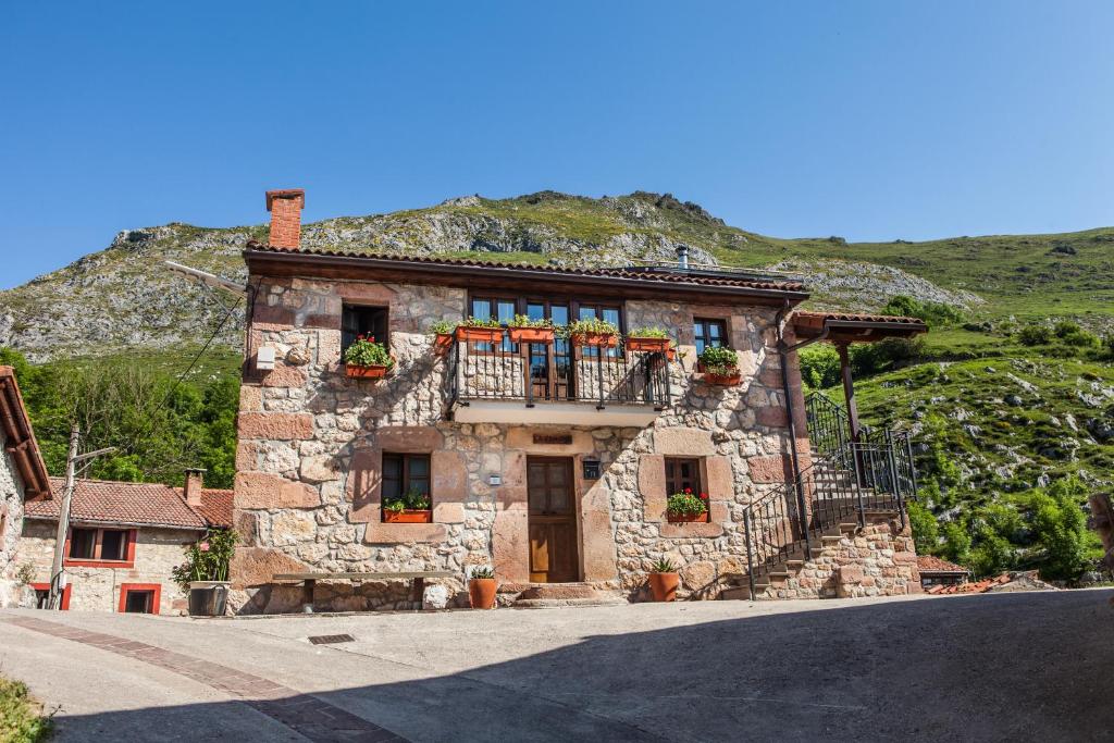 - un bâtiment en pierre avec des boîtes de fleurs sur le balcon dans l'établissement Apartamentos Rurales El Tio Pablo Picos de Europa Tresviso, à Tresviso