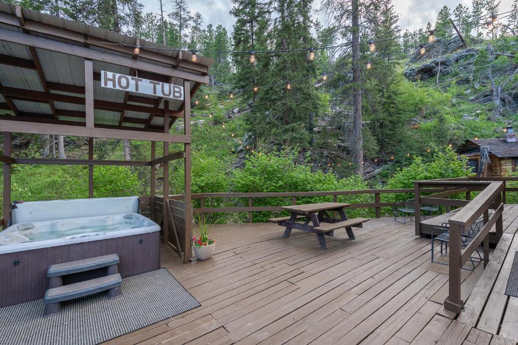 bañera de hidromasaje y mesas de picnic en una terraza de madera en Harney Camp Cabins en Hill City