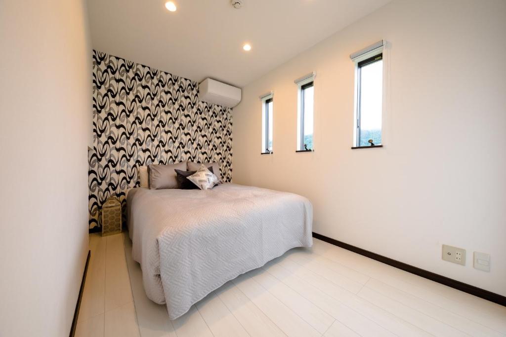 een slaapkamer met een bed en een muur met ramen bij Minamitsuru-gun - House - Vacation STAY 82405 in Fujikawaguchiko