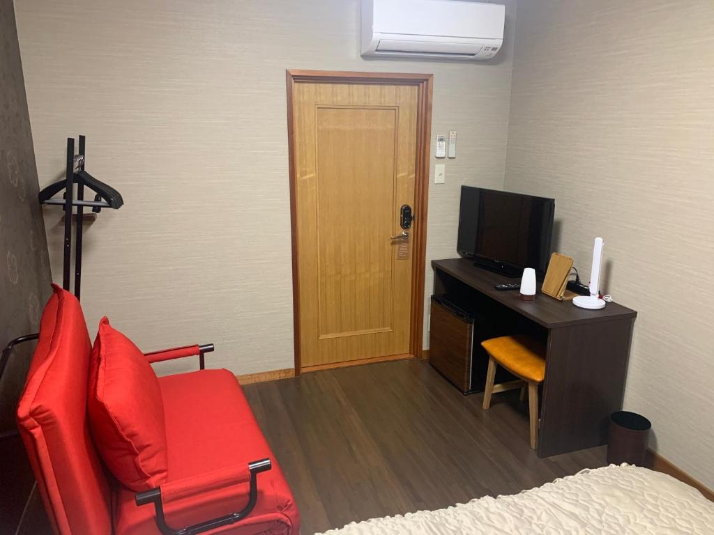 Zimmer mit einem Schreibtisch, einem roten Stuhl und einem TV in der Unterkunft Sado - Hotel - Vacation STAY 82496 in Sado