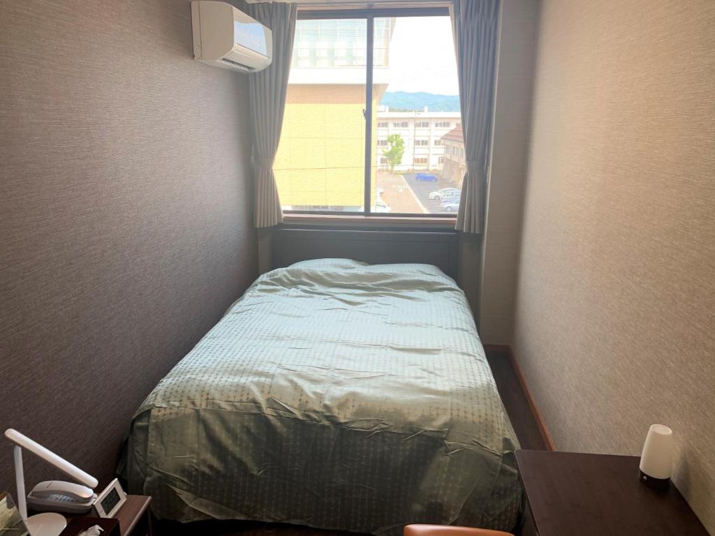 um pequeno quarto com uma cama e uma janela em Sado - Hotel - Vacation STAY 82494 em Sado