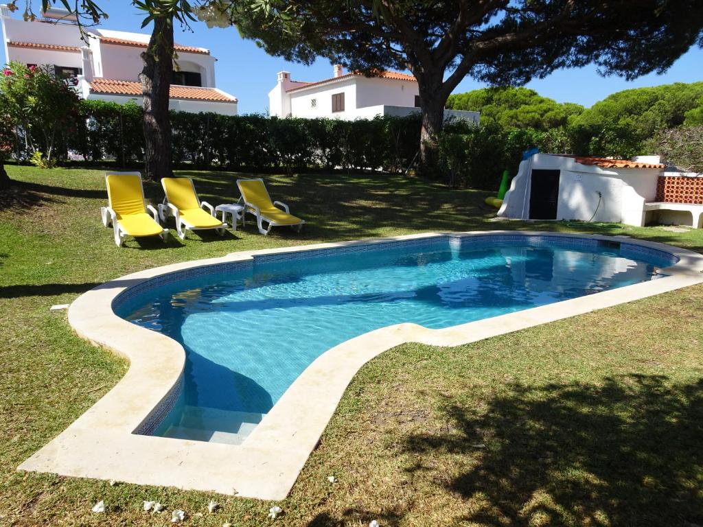 a swimming pool in a yard with chairs and a house at Vilamoura Fantástica Moradia com Piscina Privada in Vilamoura