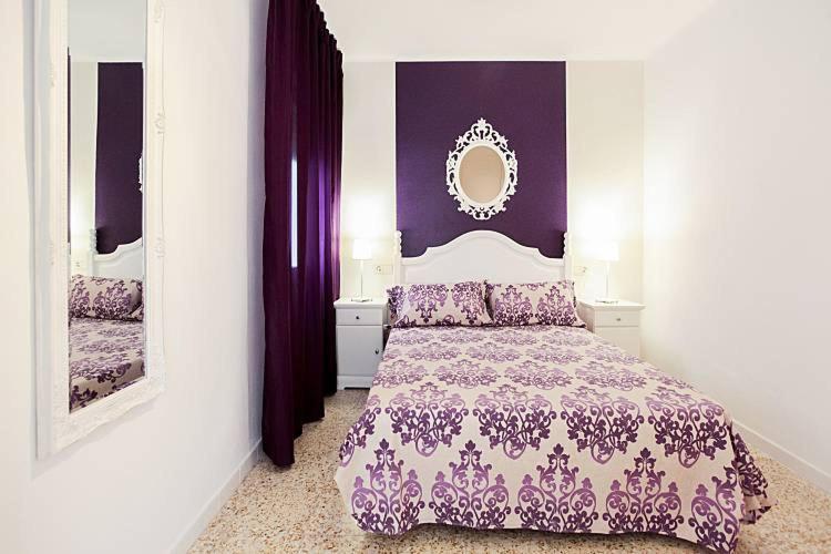 ランポーヤにあるEl piset de Paulaの紫の壁のベッド1台、鏡が備わるベッドルーム1室が備わります。