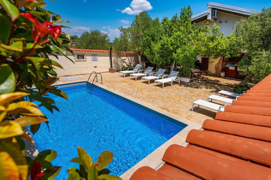 a swimming pool with lounge chairs next to a house at Olive House Zadar in Zadar