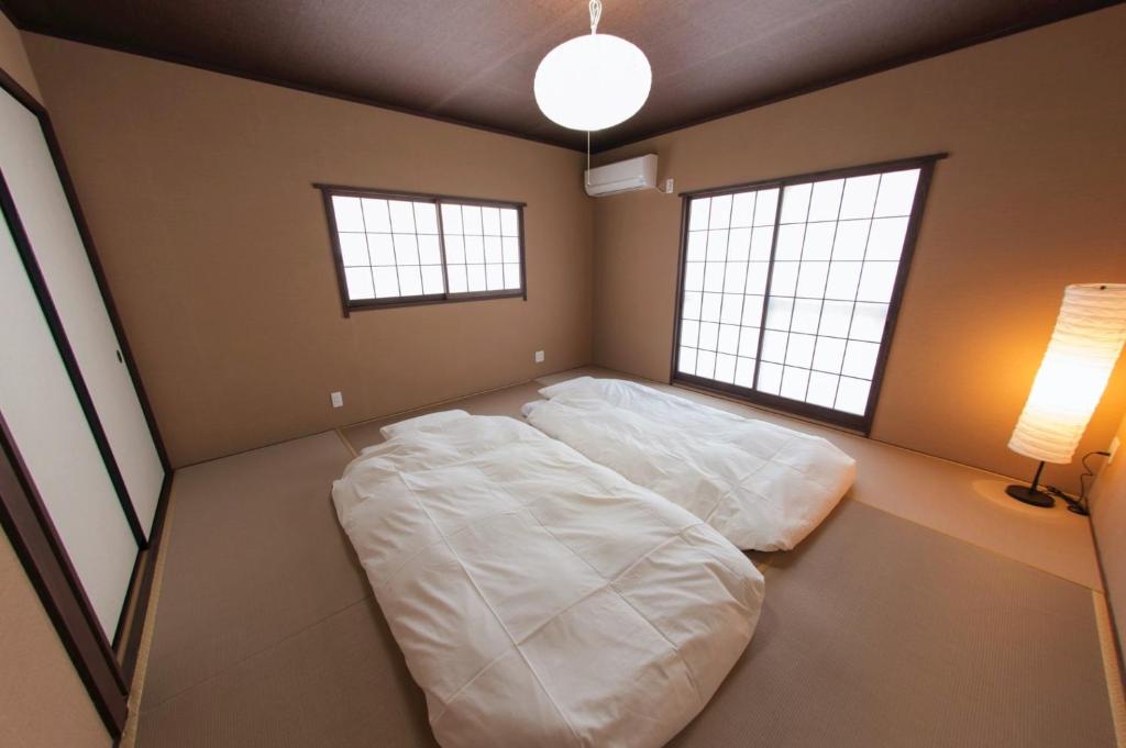 a large white bed in a room with two windows at SyukuyaYokohama Main Building 2F - Vacation STAY 82577 in Kitagatamachi