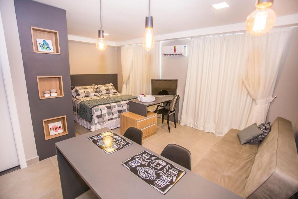 a living room with a bed and a dining room at Studio Face Norte Andar Alto - ALL1609 in Curitiba