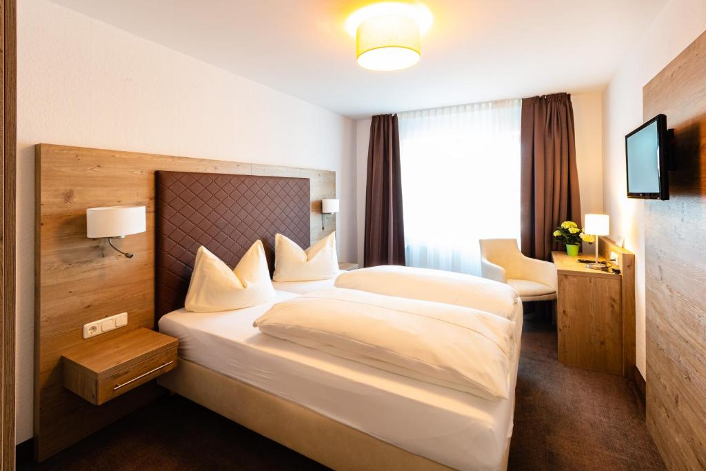 a hotel room with a large bed and a window at Hotel Gasthof Neuwirt in Holzkirchen