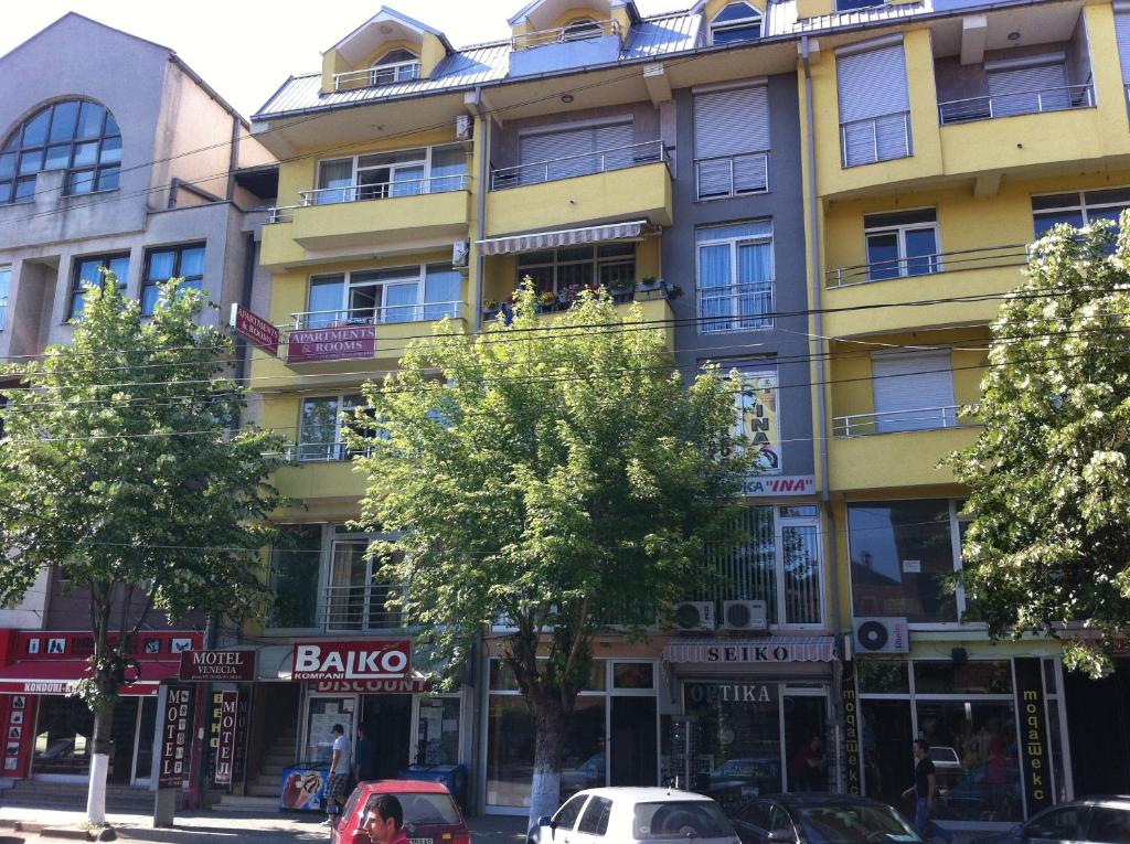 un edificio amarillo con coches estacionados frente a él en Hotel Venecia Apartments, en Struga