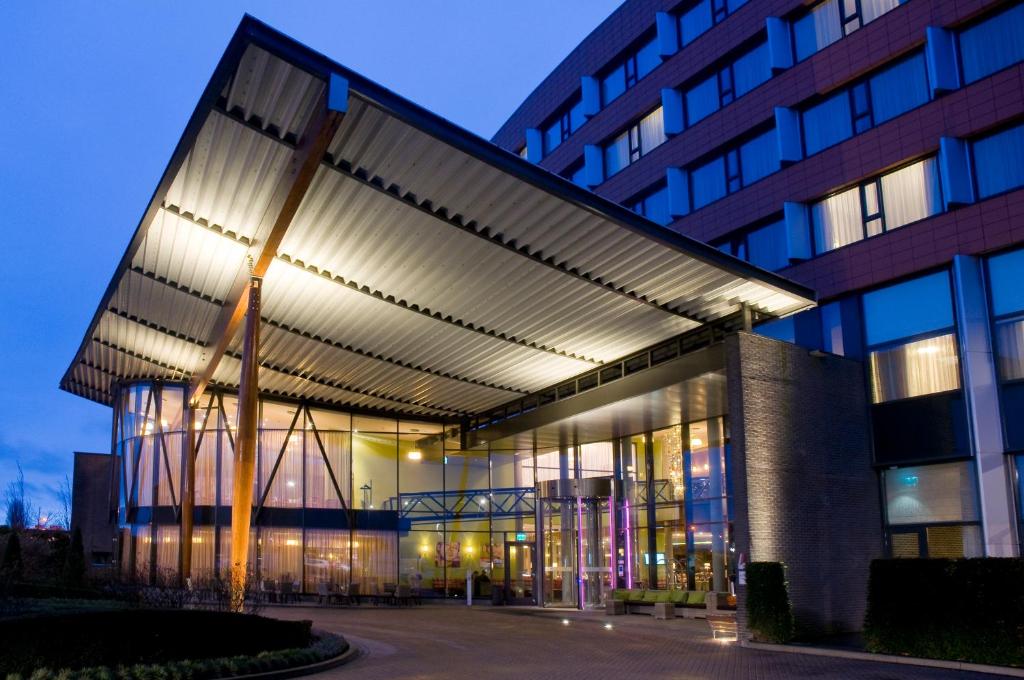 Van der Valk Hotel Rotterdam Ridderkerk في ريديرْكيركْ: مبنى به واجهة مضاءة في الليل