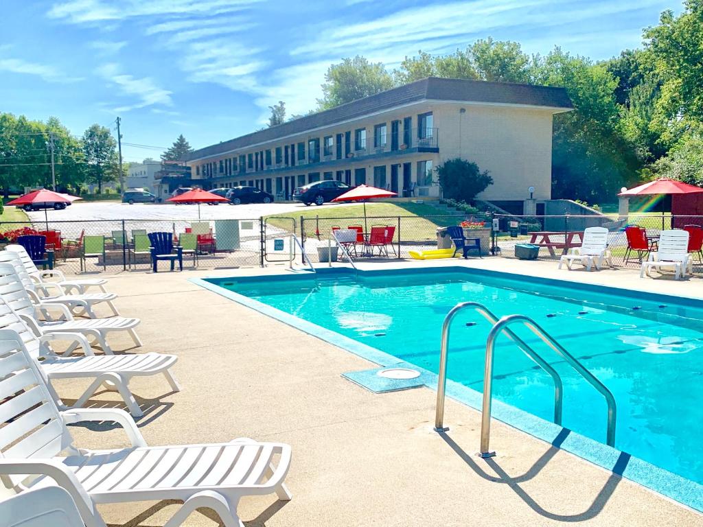 a swimming pool with chairs and tables and a building at Geneva Wells Motel in Lake Geneva
