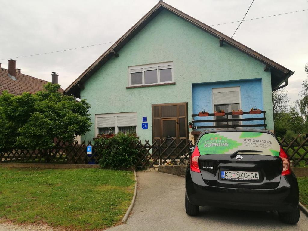 a car parked in front of a blue house at Apartman Kopriva in Koprivnica