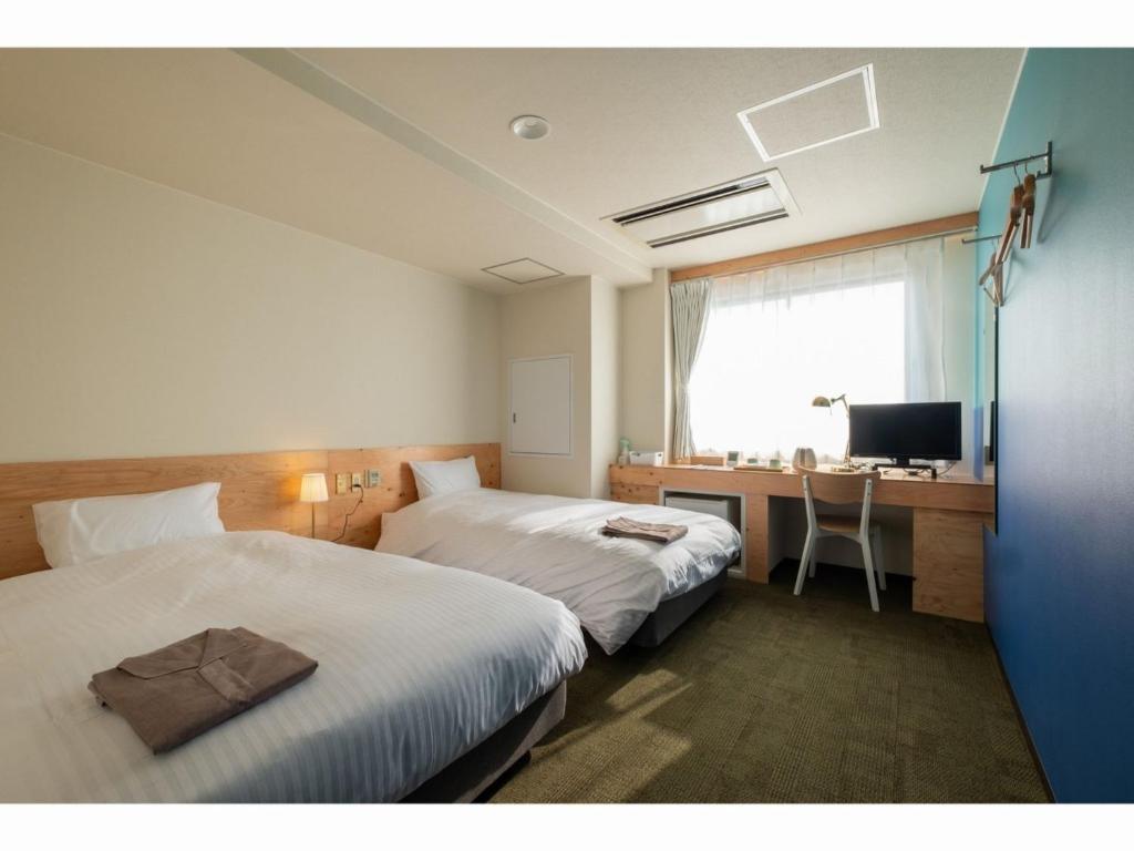 a hotel room with two beds and a desk and a television at SERENDIP HOTEL GOTO - Vacation STAY 82542 in Goto
