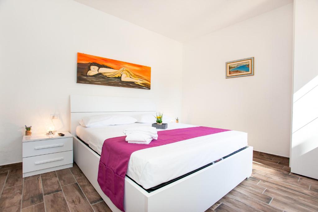 een slaapkamer met een wit bed en een paarse deken bij Terre di gallura in San Teodoro