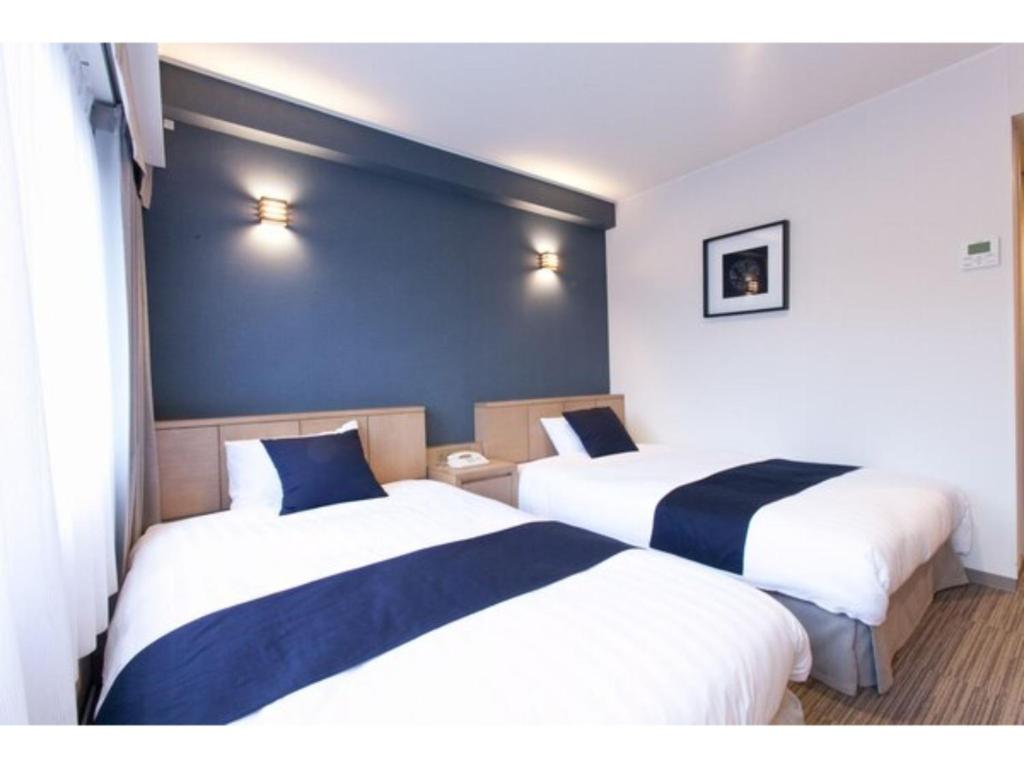 duas camas num quarto de hotel com paredes azuis em Hotel St Palace Kurayoshi - Vacation STAY 82274 em Kurayoshi